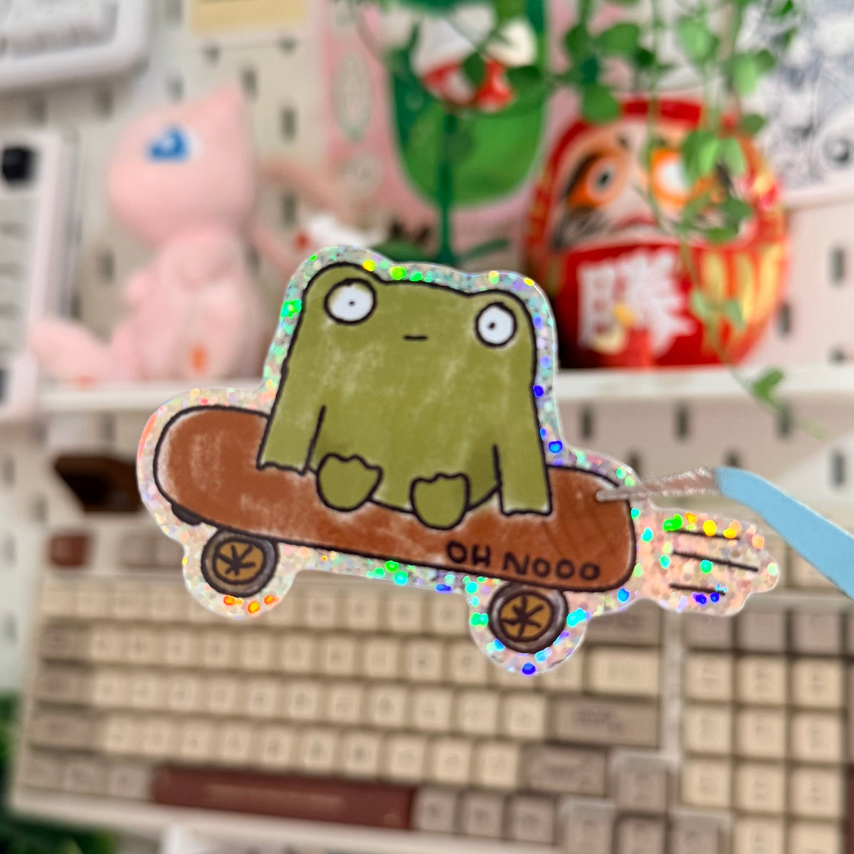 Frug Glitter Sticker featuring blobby green frog riding a skateboard.