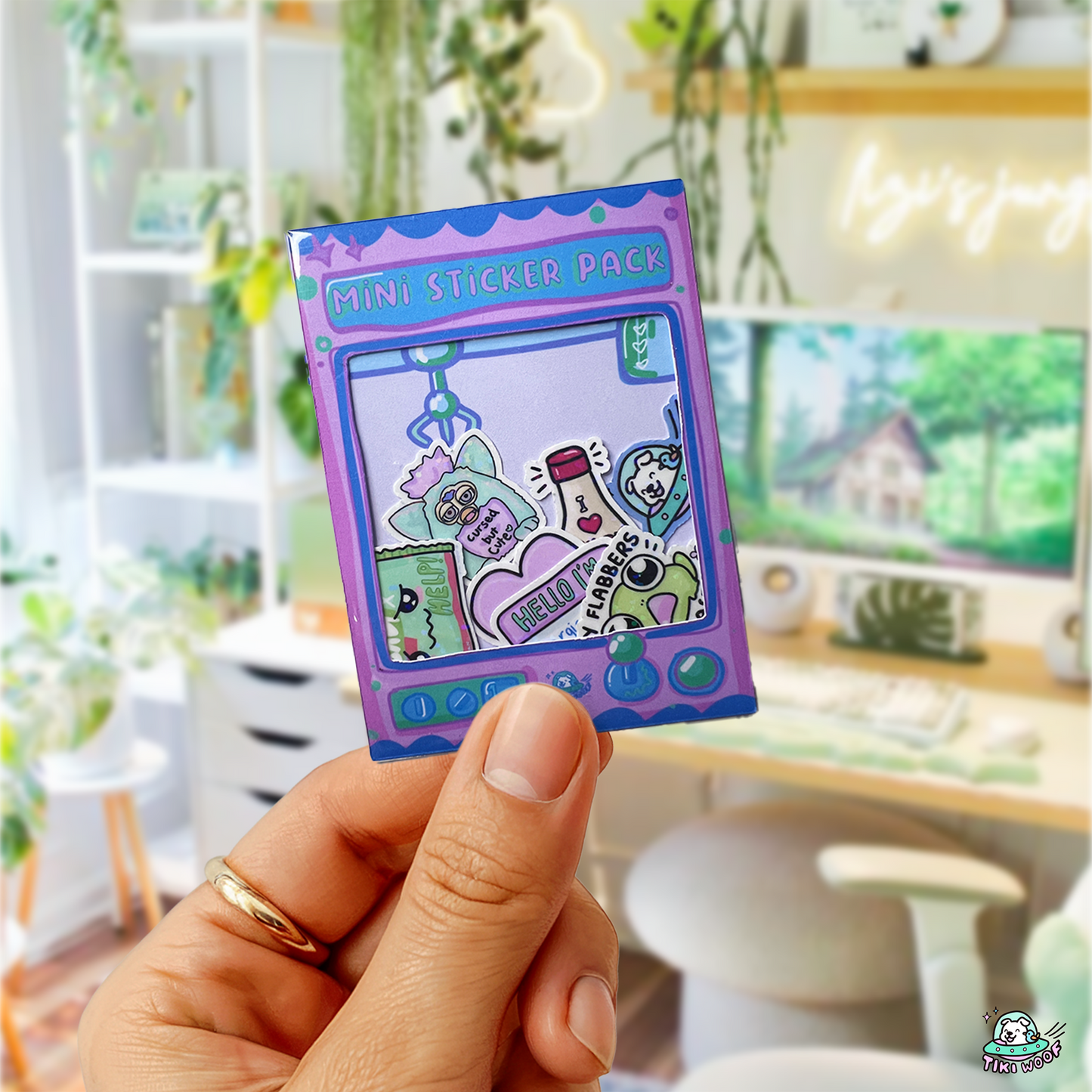 Hand holding a claw-machine-themed All Time Favs Mini Sticker Pack featuring colourful kawaii vinyl stickers inside a purple arcade-style sleeve.```