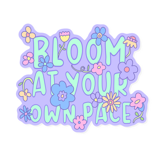 Pastel purple and mint floral sticker with the words “Bloom at your own pace,” surrounded by cute flowers. Hand-drawn design by Tiki Woof Studio.