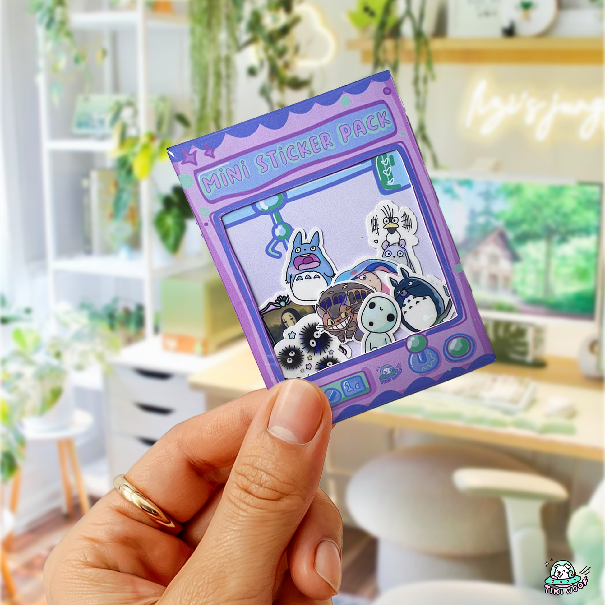Hand holding a purple claw-machine-themed mini sticker pack featuring cute Ghibli-inspired vinyl stickers with Totoro, soot sprites, and No-Face.```
