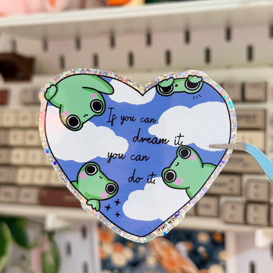 If you can dream it Glitter Sticker featuring green frogs and blue sky inside an inspirational heart design.