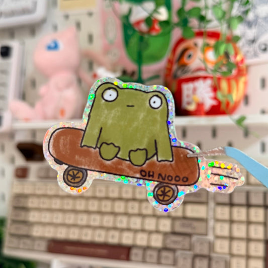 Frug Glitter Sticker featuring blobby green frog riding a skateboard.