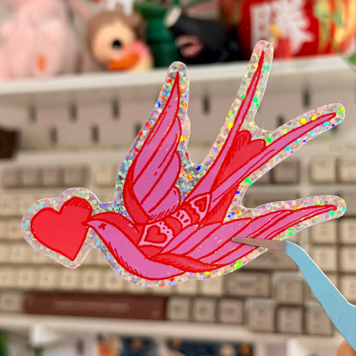 Love Doves Glitter Sticker featuring pink and red bird carrying a heart.