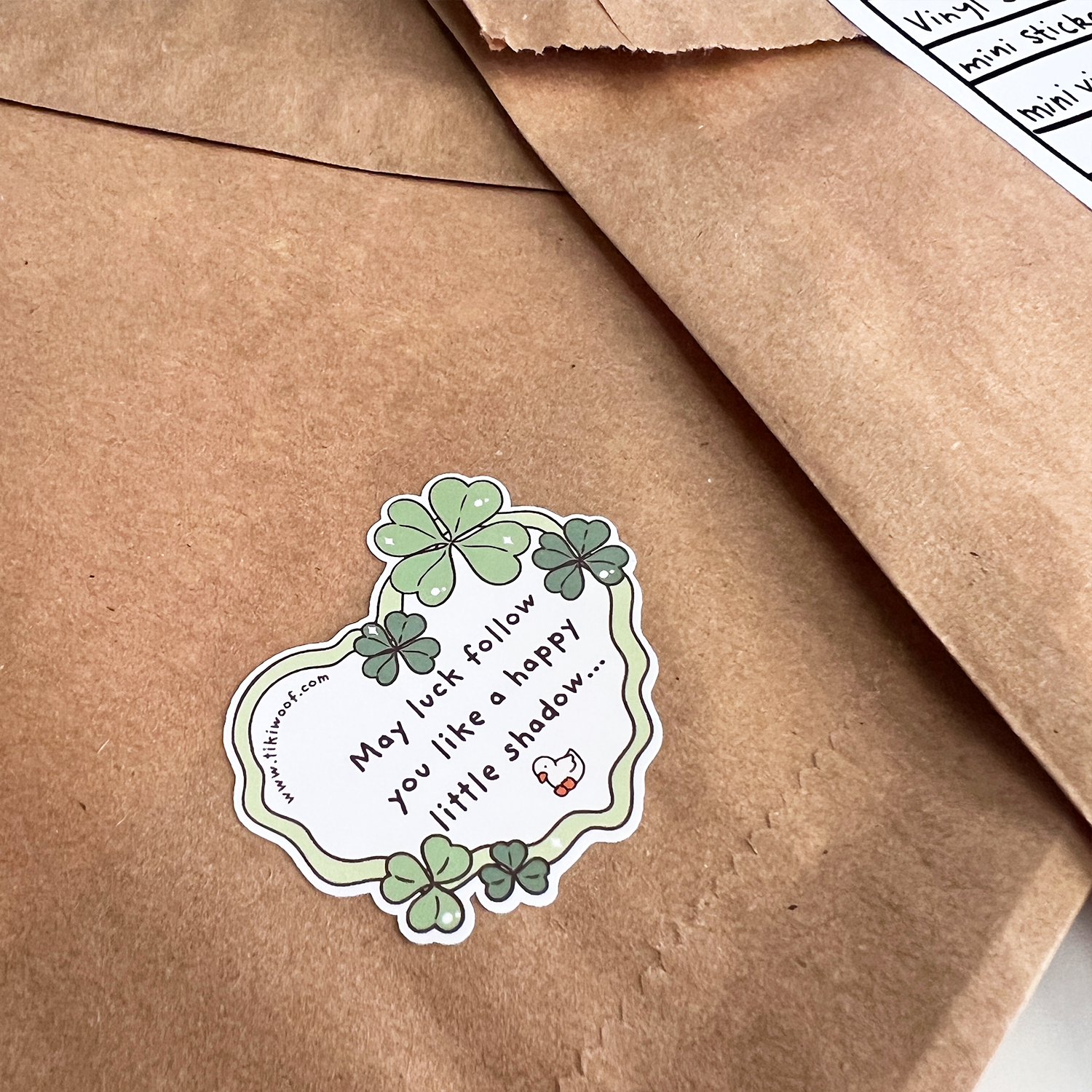 Back of Lucky Dip Lunch Bag sealed with a clover-themed good luck sticker on kraft paper.
