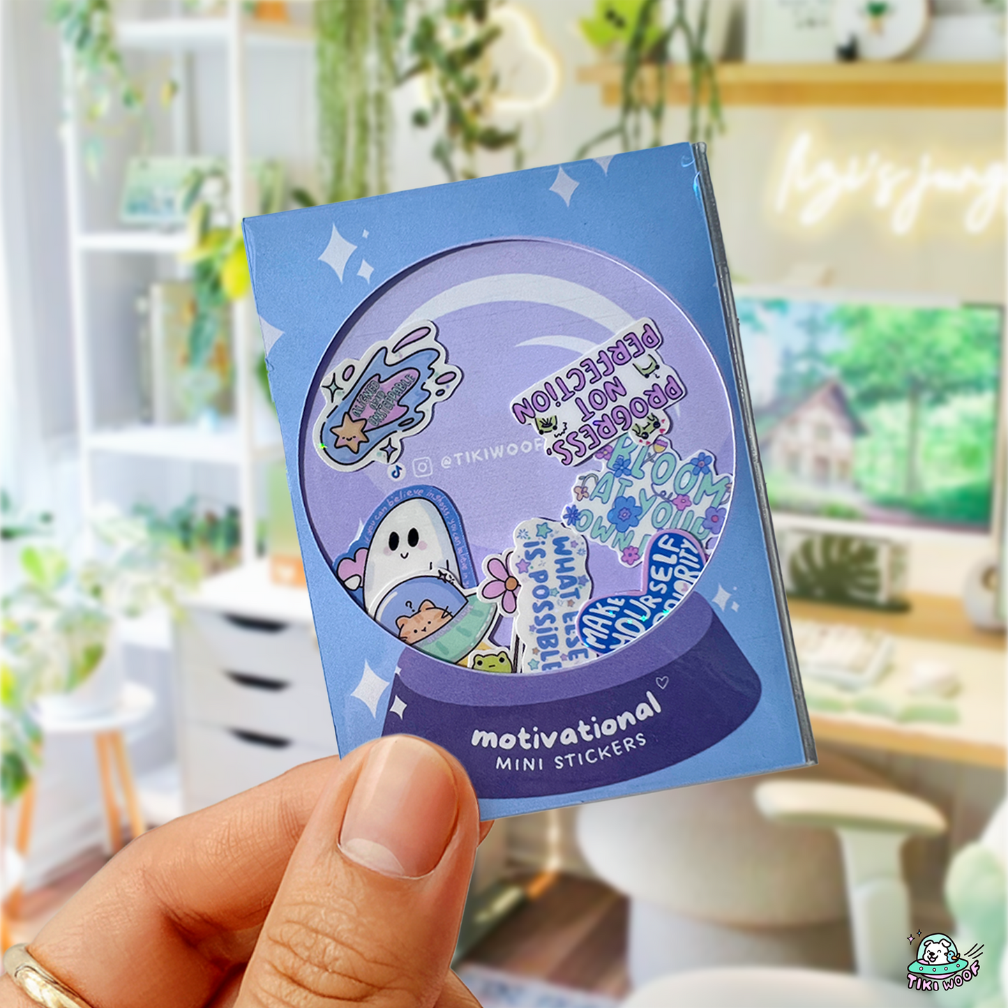 Hand holding a snow-globe-themed Motivational Mini Sticker Pack filled with pastel affirmation stickers featuring uplifting messages and cute characters.```
